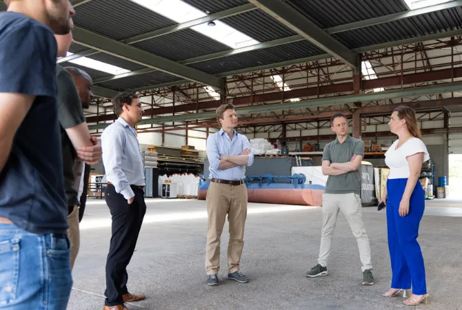 Deelnemers aan het VVD-werkbezoek in gesprek in een industriële hal.
